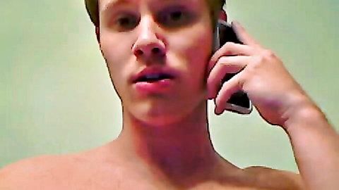 Shirtless young gay twink holding phone to ear with open mouth in webcam solo