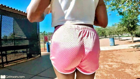 Fit ebony woman in tight pink shorts running on field, teasing ass view