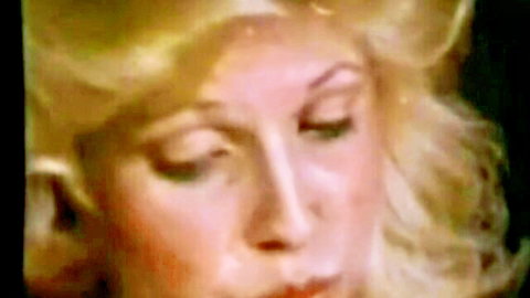 Seductive blonde with heavy makeup and parted lips in intense retro closeup tease