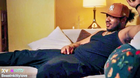 Handsome black man in orange Yankees hat lounging in black tank top