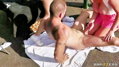 Busty woman in pink shorts strokes bald muscular man's hard cock outdoors on towel