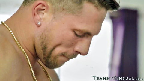 Muscular bearded man with gold chain necklace gazes intensely in close-up