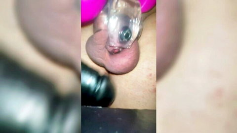 Close-up of small penis and balls tortured with clear and pink sex toys until cum