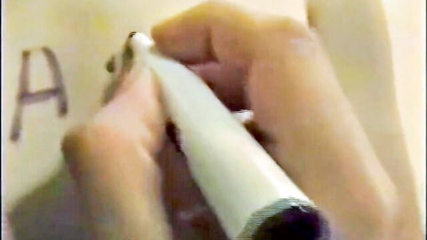 Goth hand writing humiliating grade on chalkboard in domination scene