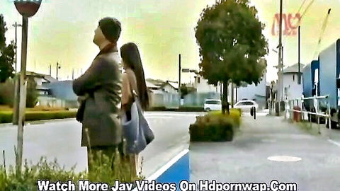 Japanese wife embraced by man on street near bus in intimate JAV moment