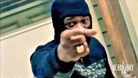 Masked black man in balaclava pointing finger at camera with gold ring intensely