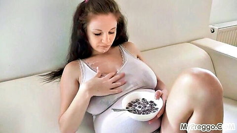 Brunette with big tits in white tank top holding yogurt bowl over chest