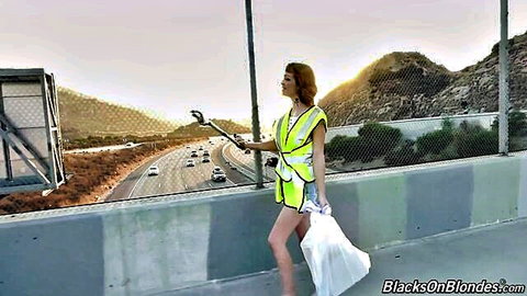 Aliya Brynn in yellow safety vest on highway overpass, sexy outdoor tease