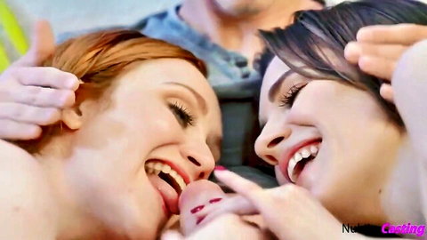 Redhead licks brunette's tongue in playful threesome casting kiss