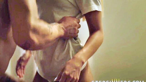 Muscular man undressing slim woman in white t-shirt from behind