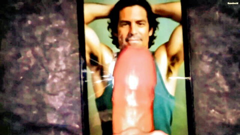 Muscular Latino man smiling in tank top, posing with large red dildo
