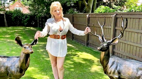 Curvy blonde MILF in open white blouse teasing big tits while holding deer antlers in garden