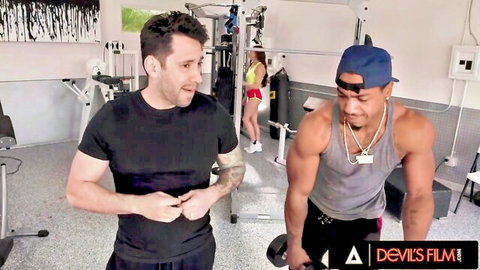 Kira Noir in gym swingers scene with muscular white and black men