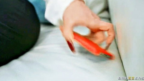 Alura Jenson's hand with red nails gripping orange toy in naughty babysitter scene