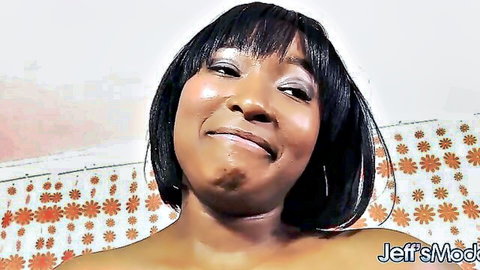 Smiling ebony MILF with bare tits and cleavage teasing on bed