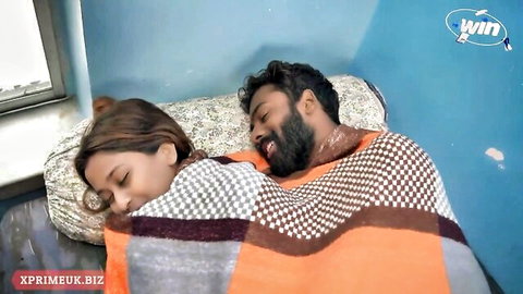 Intimate Desi couple spooning under blanket in cozy bedroom