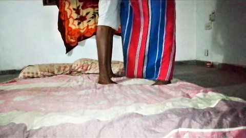 Sri Lankan woman in striped skirt standing barefoot on bed
