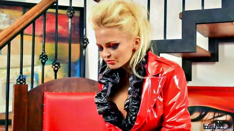 Blonde dominatrix in red latex jacket showing deep cleavage