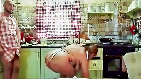 Curvy naked woman in apron bent over kitchen counter exposing huge ass and pussy to voyeur man