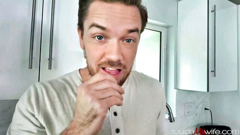 Handsome husband licks fingers teasingly in kitchen after touching wife