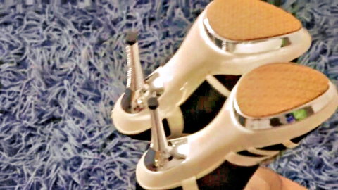 Closeup of sexy white high heels with silver accents on blue carpet, foot fetish tease