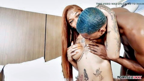 Tattooed black tgirl and man embracing topless in intimate kiss