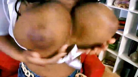 Ebony woman with massive black boobs spilling out of white top, hands cupping her huge tits