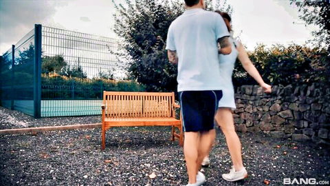 Tennis coach and sexy student in short dress on outdoor court lesson