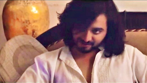 Handsome Indian man with long wavy hair in open white embroidered shirt, seductive gaze