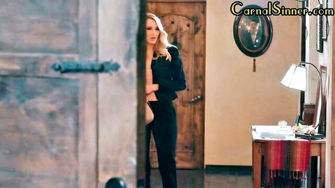 Blonde woman in black suit peeking seductively from bedroom door