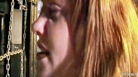 Blonde woman in intense LESDOM bondage close-up, chains visible