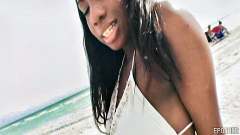 Smiling ebony woman in white bikini top at sunny beach