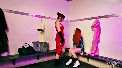 Brunette in tight red dress stands over redhead babe in knee socks in sexy locker room pose