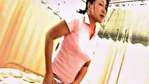 Japanese nurse in pink shirt bending over hospital bed with pained expression