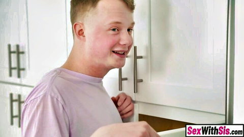 Young freckled stepbrother smiling while opening kitchen drawer in teasing stepsis video