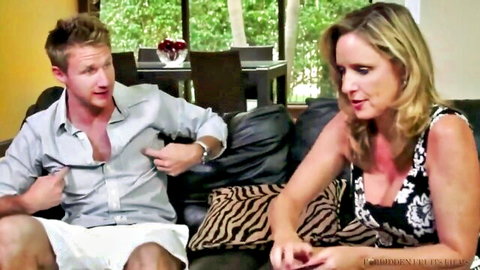 Blonde MILF in cleavage dress chats with young stud on couch in Milf Hunter scene
