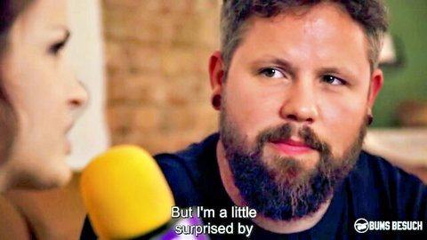 Bearded man and surprised brunette woman in interview holding yellow microphone