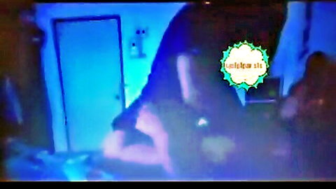 Miss Sasi squats teasingly in dim blue-lit room, revealing curves