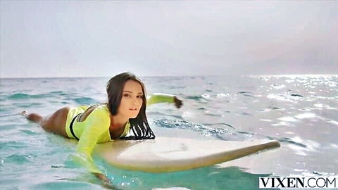 Sonya in revealing yellow swimsuit on surfboard in ocean