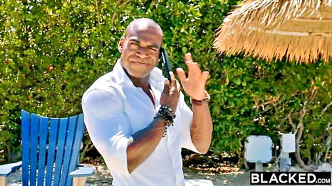 Muscular Black stud on phone smiling seductively at beach resort