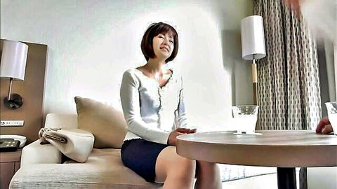 Mature Japanese beauty in white blouse and black skirt smiling on couch
