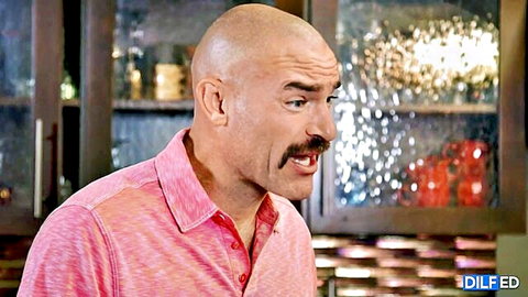 Bald DILF daddy with mustache smirks intensely in pink shirt kitchen scene