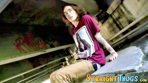 Sean Johansen, long-haired skater guy in t-shirt and pants under graffiti bridge