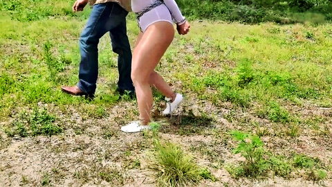 Carissa Dumond in metal bondage outdoors, hands cuffed behind back