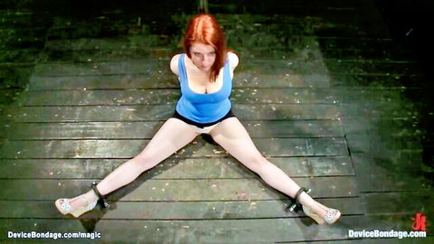 Redhead bound in blue top with legs spread wide in BDSM restraints