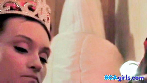 Brunette bride in sparkling tiara and veil gazes intensely with aroused eyes during wedding sex