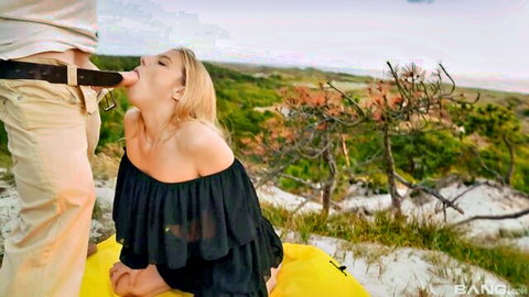 Blonde babe kneels outdoors on yellow blanket sucking man's hard cock passionately