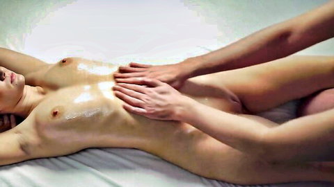 Naked Asian teen spread eagle on table with hands massaging cum-covered tits and wet pussy