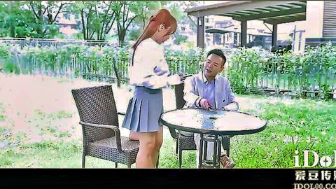 Busty Asian amateur in schoolgirl skirt teases seated man outdoors