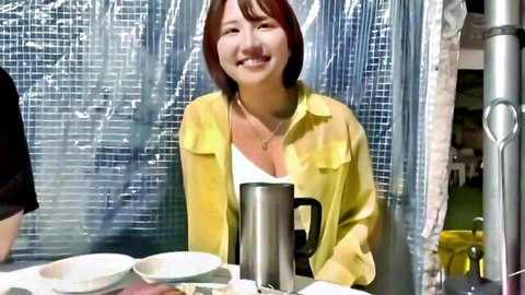 Cute Asian babe with big cleavage in yellow jacket smiling at table
